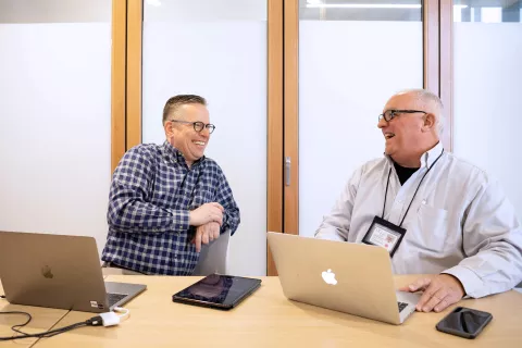 UCSF Student Disability Services (SDS) co-directors Clay Littrell and Timothy Montgomery are sitting at a table with their laptops open.